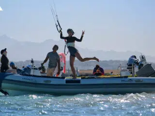 Uczestnicy kite campu KiteAway wypoczywają na motorówce Legacy z widokiem na góry - idealny wyjazd kitesurfingowy.