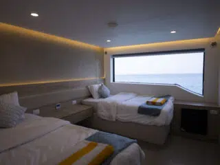 Nowoczesna, jasna sypialnia z dwoma łóżkami, widokiem na morze i ręcznikami-idealne miejsce na relaks po wyjazdach kitesurfingowych z KiteAway.