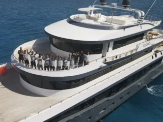 Uczestnicy wyjazdu kitesurfingowego KiteAway na jachcie LEGACY, uśmiechnięci i gotowi na kite camp, z lazurowym morzem w tle.