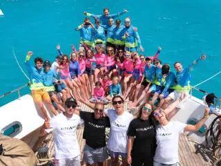 Grupa uczestników KiteAway w kolorowych koszulkach na pokładzie łodzi podczas wyjazdu kitesurfingowego - kite camp.