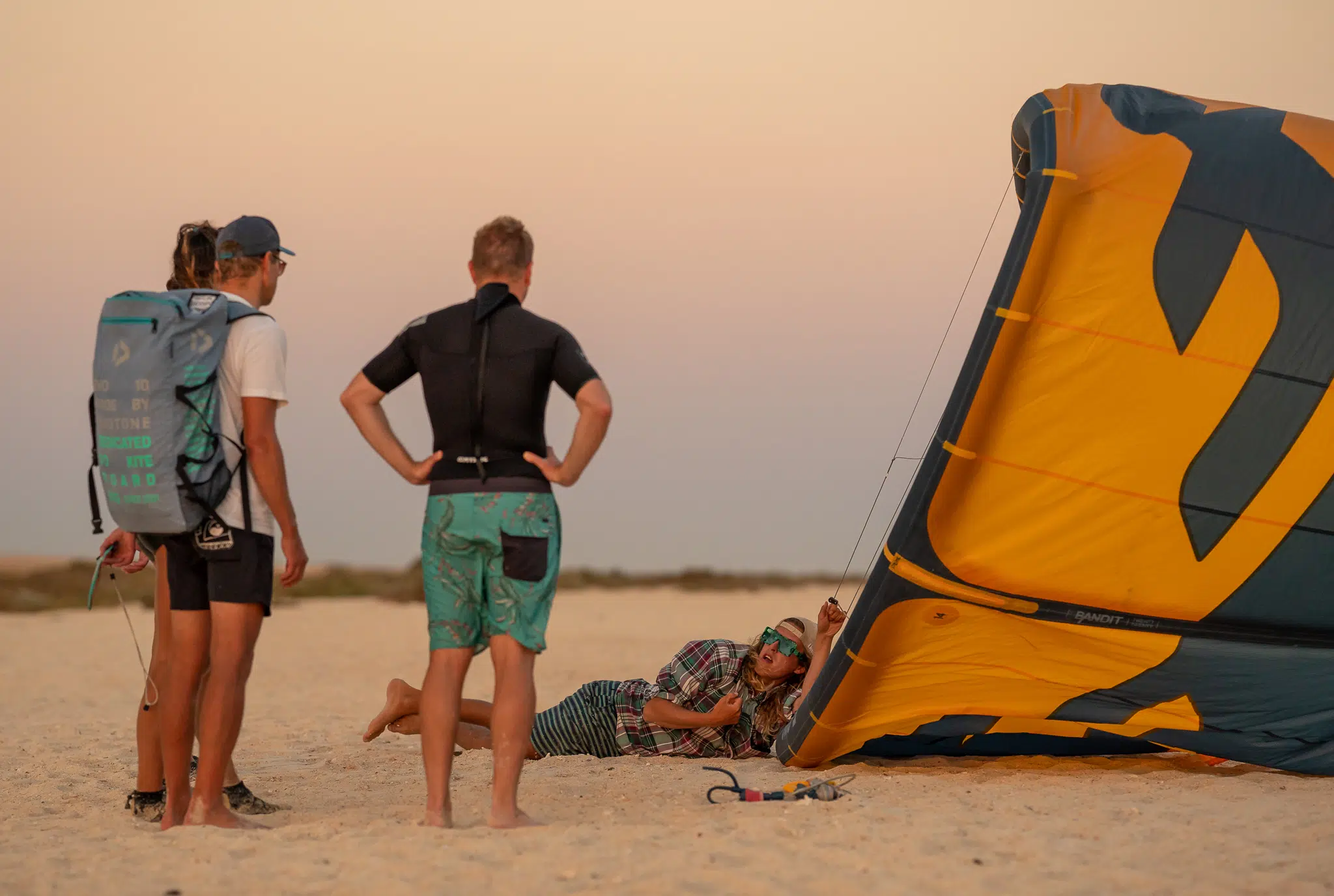 Grupa na plaży szykuje się do zachodu słońca z latawcem - idealny klimat na wyjazdy kitesurfingowe z KiteAway.