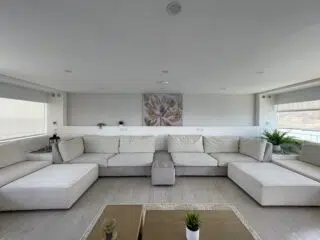 Nowoczesny salon z dużymi, beżowymi sofami, idealny na planowanie wyjazdu szkoleniowego na wakacje z kitesurfingiem z KiteAway.