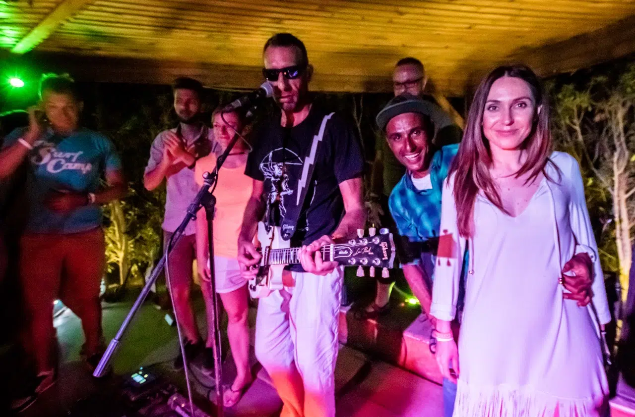 Uczestnicy wyjazdu kitesurfingowego KiteAway w El Gounie bawią się wieczorem na kite campie, otoczeni kolorowymi światłami.