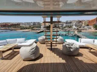 Pokład jachtu KiteAway z białymi kanapami, widokiem na lazurową wodę i plażę - idealne miejsce na wyjazdy kitesurfingowe.