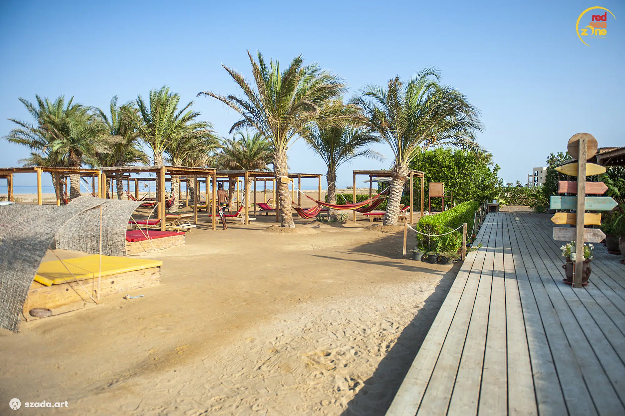 Plaża z palmami w El Gounie, hamaki i cabany przy drewnianym pomoście - idealne miejsce na wakacje z kitesurfingiem KiteAway.
