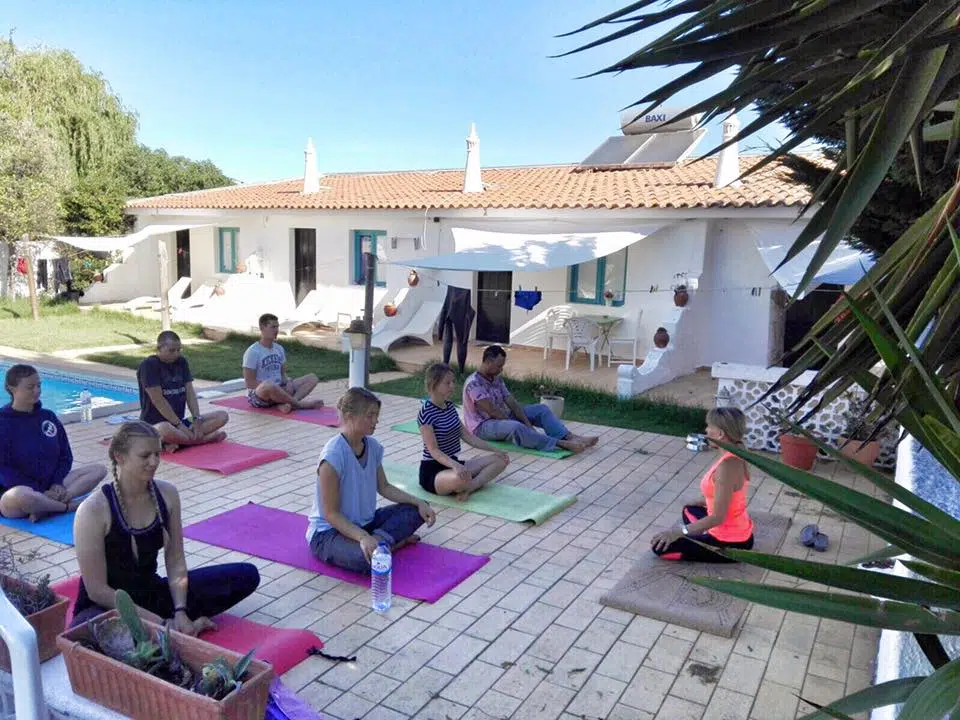 Grupa uczestników kursu kitesurfingu relaksuje się na matach jogi przy basenie. Idealny początek obozu kite'owego z KiteAway w Portugalii.