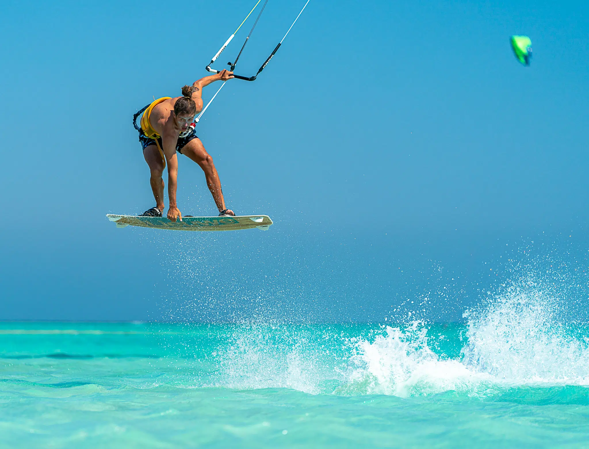 Kitesurfer wykonuje skok nad turkusową wodą - idealne warunki na wyjazdy kitesurfingowe z KiteAway.