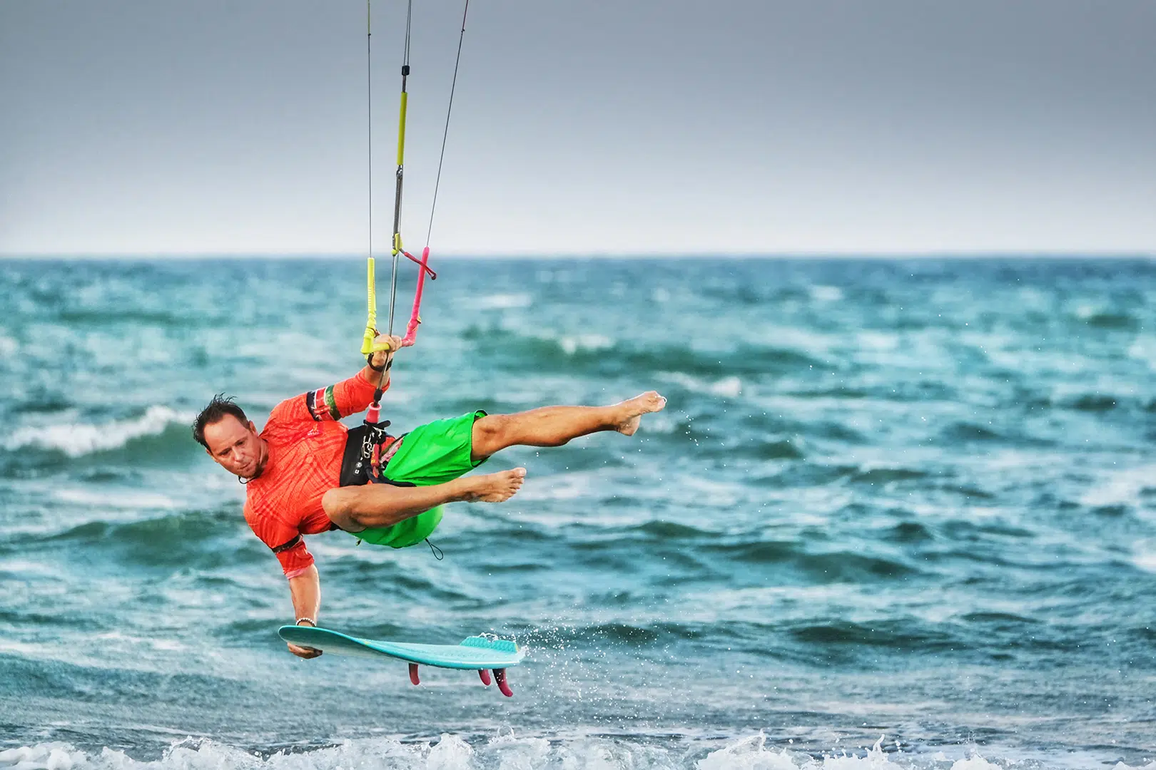 Kitesurfer w czerwonej koszulce wykonuje trick nad falami na Sri Lance podczas wyjazdu kitesurfingowego z KiteAway.