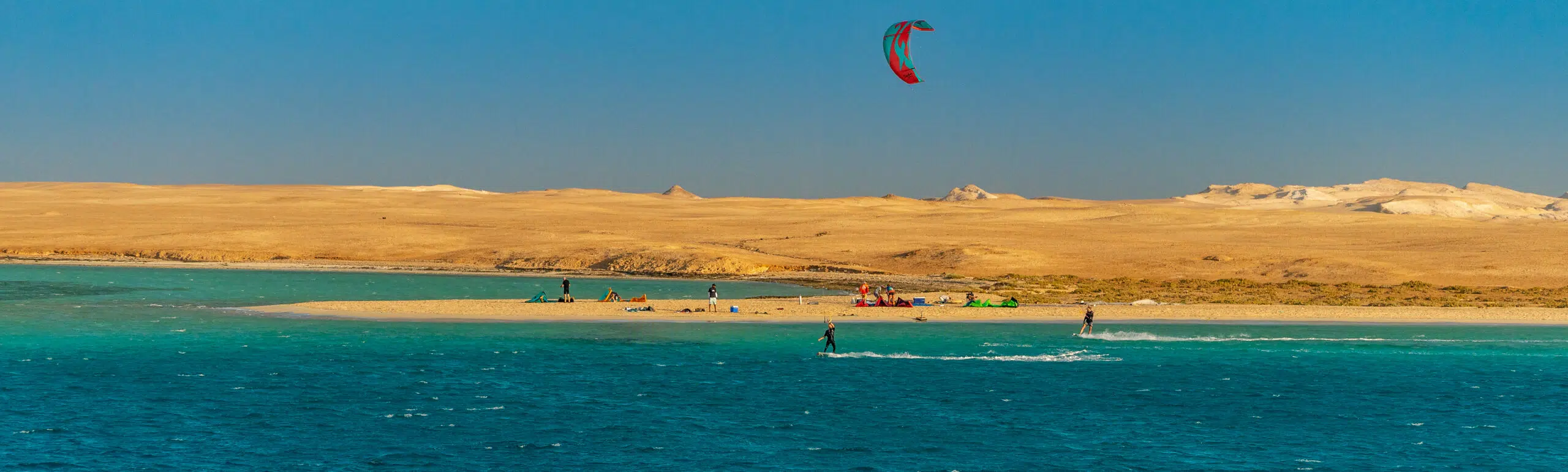 Turkusowa laguna z kitesurferami i plażą przy złotych wydmach - idealny spot na wyjazdy kitesurfingowe z KiteAway.