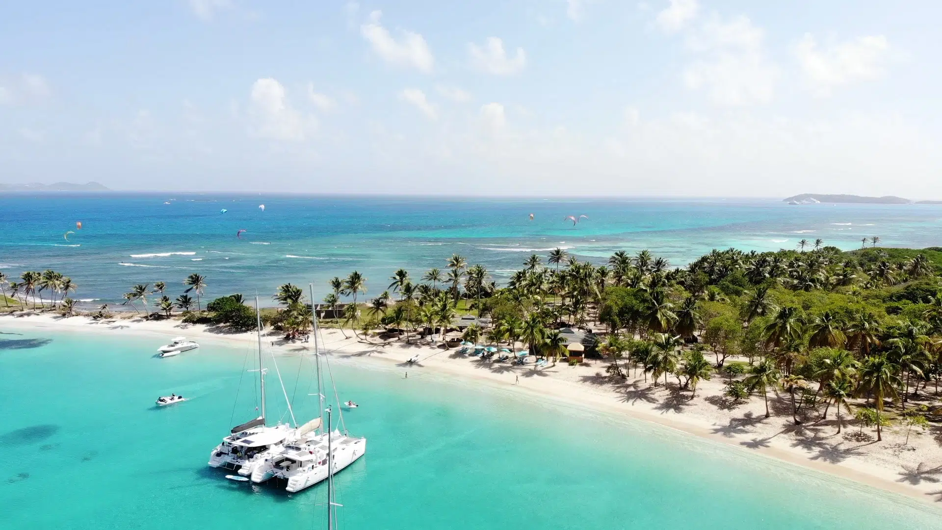 Tropikalna plaża z palmami i turkusową wodą, żaglówki, kitesurferzy - idealny spot na wyjazdy kitesurfingowe z KiteAway.