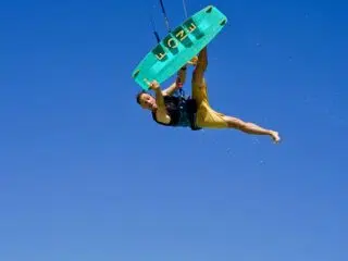 Kitesurfer w żółtych szortach na zielonej pustyni nad wodą na kite camp KiteAway. Idealny klimat na wyjazdy kitesurfingowe.