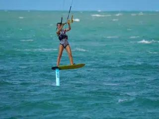 Wyjazd kitesurfingowy z KiteAway: osoba na wodolot płynie po turkusowej wodzie, trzymając bar, przy pięknej pogodzie.