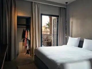 Jasny, minimalistyczny pokój hotelowy w El Gounie z widokiem na palmy - idealne miejsce na relaks po dniu pełnym kitesurfingu Egipt.