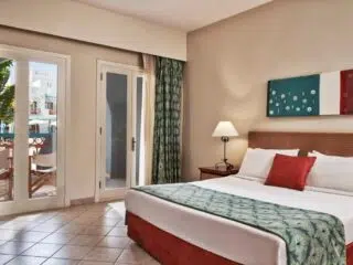 Jasny pokój hotelowy z dużym łóżkiem, balkonem i widokiem - idealny na relaks po kite campie KiteAway lub kursie kitesurfingu.