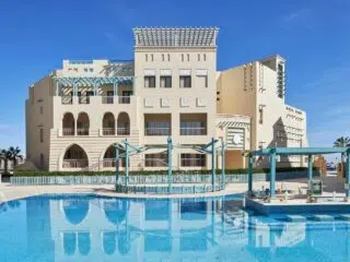Beżowy hotel z łukowatymi oknami przy basenie w El Gouna - idealny relaks po szkoleniu kite z KiteAway, wakacje z kitesurfingiem.