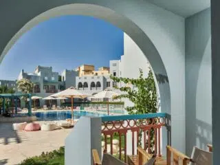 Widok z zacienionego tarasu na basen przy nowoczesnych budynkach El Gouna - relaks po wyjeździe kitesurfingowym z KiteAway.