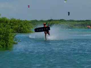 Kiteboarder w pomarańczowym kasku trenuje na tle laguny z ekipą KiteAway podczas wyjazdu kitesurfingowego; kurs kitesurfingu.