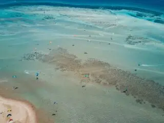 Widok z lotu ptaka na El Gouna kite spot: kitesurferzy jeżdżą na turkusowych płyciznach, ławicach i rafach. Idealny na wyjazdy kitesurfingowe z KiteAway.