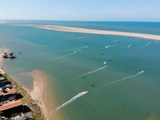 Widok na kite camp nad turkusowym morzem - idealny spot na wyjazdy kitesurfingowe z KiteAway. Plaża, surferzy i kursy kite.