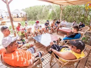 Uczestnicy wyjazdu KiteAway w El Gouna odpoczywają po kitesurfingu, siedząc w cieniu na tarasie podczas wakacji z kitesurfingiem.