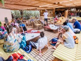 Grupa uczestników kursu kitesurfingu na El Gouna słucha prelekcji pod pergolą podczas wyjazdu kitesurfingowego z KiteAway.