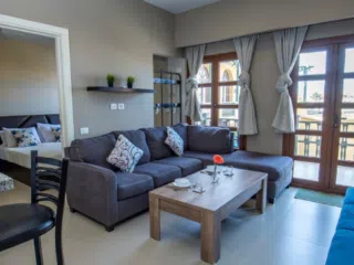 Nowoczesny salon z szarą sofą i widokiem na sypialnię, idealny relaks po wyjazdach kitesurfingowych z KiteAway.pl.