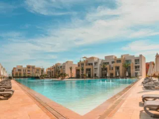 Basen, leżaki i palmy przy nowoczesnym ośrodku - idealne miejsce na wakacje z kitesurfingiem i wyjazdy kitesurfingowe z KiteAway.