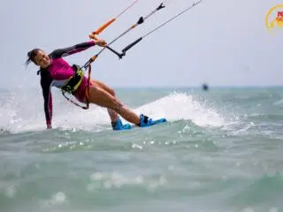 Uśmiechnięta kobieta na kite campie KiteAway w El Gouna, kitesurfing Egipt, podczas dynamicznego ślizgu po falach.
