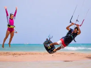 Mężczyzna uprawia kitesurfing w El Gounie, kobieta skacze na plaży. Idealny spot na wyjazdy kitesurfingowe z KiteAway.
