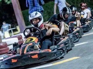 Grupa w kaskach jedzie gokartami nocą, gotowa do startu - emocje jak na wyjeździe kitesurfingowym KiteAway w El Gounie.