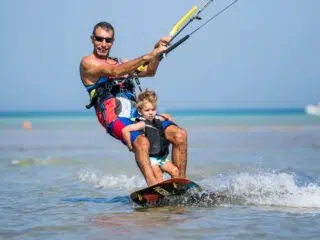 Mężczyzna i dziecko w kamizelkach na płytkiej wodzie w El Gounie - rodzinne wakacje z kitesurfingiem KiteAway, Egipt.