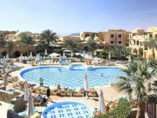 Basen w kształcie serca w otoczeniu palm i leżaków na egzotycznym kite campie KiteAway - idealny relaks po kursie kitesurfingu.