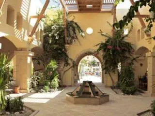 Przestronny dziedziniec KiteAway na kite camp: fontanna, pergola i rośliny-idealne miejsce na wyjazdy kitesurfingowe.