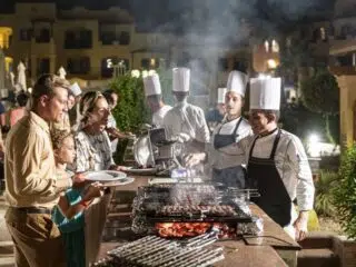 Uczestnicy KiteAway podczas wakacji z kitesurfingiem stoją w kolejce do bufetu z grillowanymi szaszłykami po dniu na kite spocie.