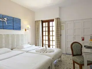 Jasny pokój hotelowy z dwoma łóżkami, dekoracją łabędzia-idealny na relaks po wyjeździe kitesurfingowym KiteAway.