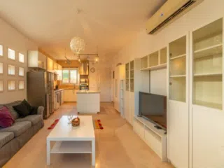 Jasny salon z aneksem, białymi meblami i szarą sofą - idealny relaks po kursie kitesurfingu lub wyjeździe KiteAway.