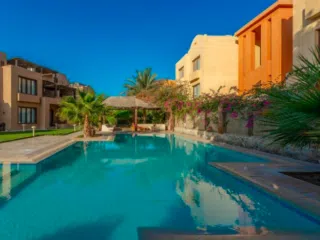 Basen otoczony palmami i kwiatami, nowoczesne budynki; idealny relaks po kite tripie z KiteAway lub wakacjach z kitesurfingiem.