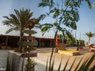 Słoneczny kite spot w El Gouna z palmami, deptakiem i kolorowymi flagami - idealne miejsce na wyjazdy kitesurfingowe z KiteAway.