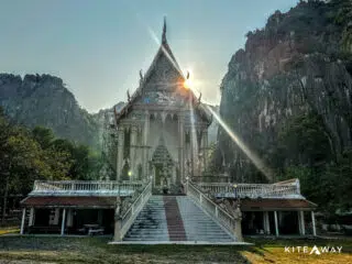 Słoneczny, egzotyczny krajobraz z tajską świątynią wśród klifów i zieleni - idealne miejsce na kite trip z KiteAway.