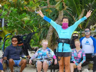 Grupa 5 osób na plaży z kite sprzętem i roślinami, cieszy się wyjazdem kitesurfingowym KiteAway - wakacje z kitesurfingiem.