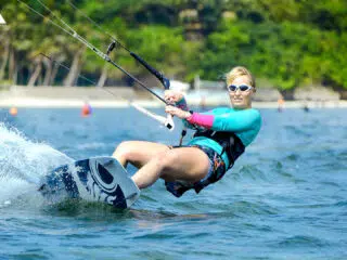 Kobieta w okularach i niebieskiej lycrze kitesurfuje podczas wyjazdu z KiteAway; wakacje z kitesurfingiem, kite trip.
