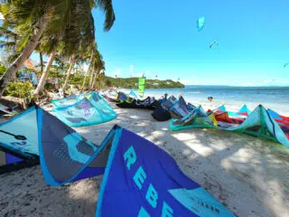 Kolorowe latawce na plaży z palmami, KiteAway i kursy kitesurfingu na tle morza - idealne wakacje z kitesurfingiem.