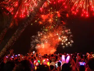 Uczestnicy wyjazdu kitesurfingowego KiteAway oglądają fajerwerki na plaży nocą, wśród palm, świętując kite trip.