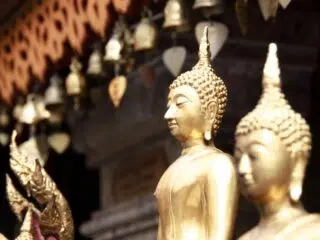 Rząd złotych posągów Buddy na tle rozmytych ozdób, klimat wyciszenia jak podczas wyjazdu kitesurfingowego z KiteAway.