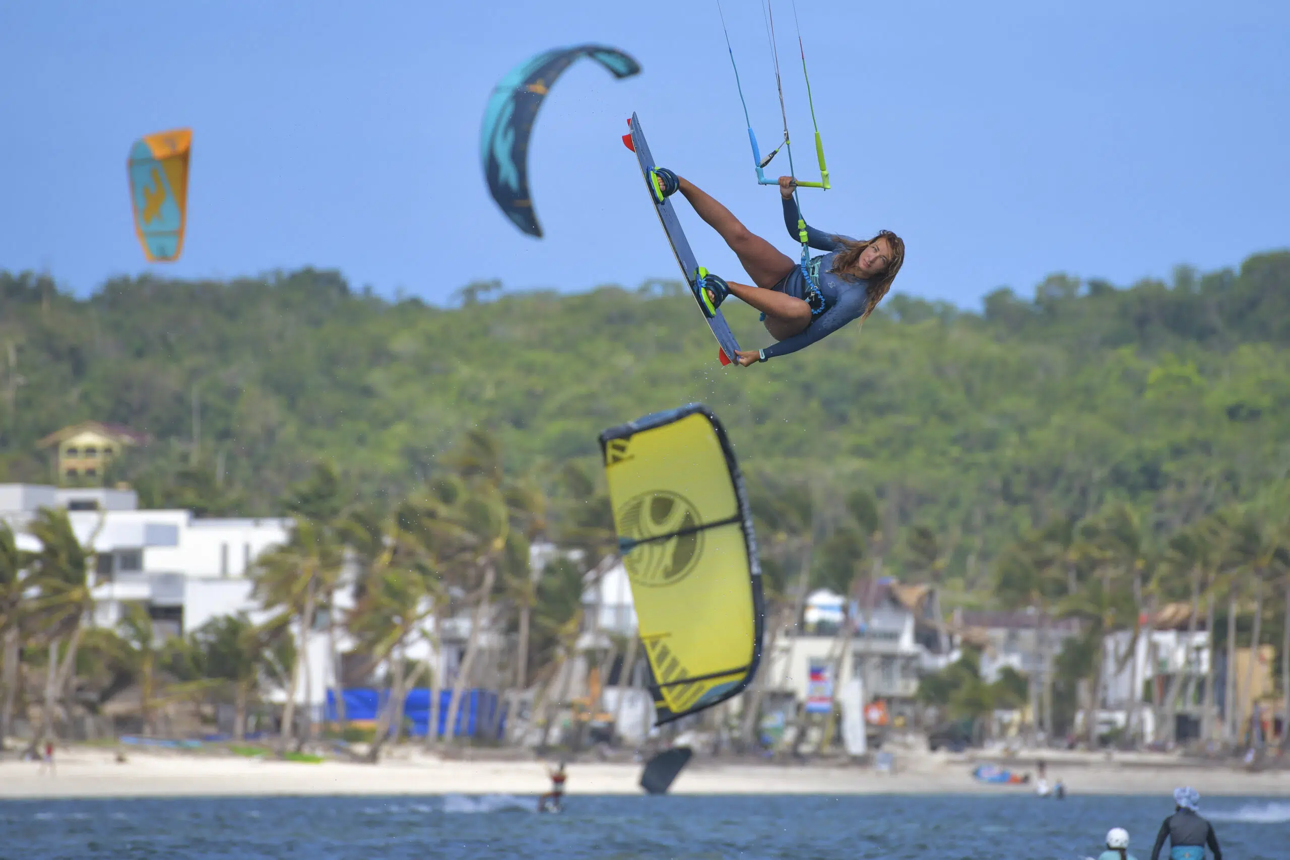 Kitesurfer w powietrzu na tle kolorowych latawców; atmosfera kite camp KiteAway - idealne wakacje z kitesurfingiem.