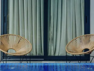 Dwa wiklinowe fotele przy niebieskim basenie - idealne miejsce na relaks po kursie kitesurfingu z KiteAway lub kite camp.