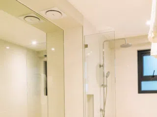 Nowoczesna łazienka z dużym lustrem, przeszklonym prysznicem i jasnymi płytkami - relaks po kite camp lub wakacjach z kitesurfingiem.