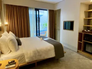 Nowoczesny pokój hotelowy z dużym łóżkiem i balkonem z widokiem na basen - idealny na wyjazdy kitesurfingowe z KiteAway.