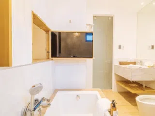 Nowoczesna łazienka w apartamencie KiteAway - idealna na relaks po wyjeździe kitesurfingowym; białe kafle, wanna, TV.