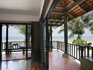 Taras z widokiem na plażę kitesurfingową, idealny na chill po wyjazdach kitesurfingowych z KiteAway; palmowe i błękitne niebo.